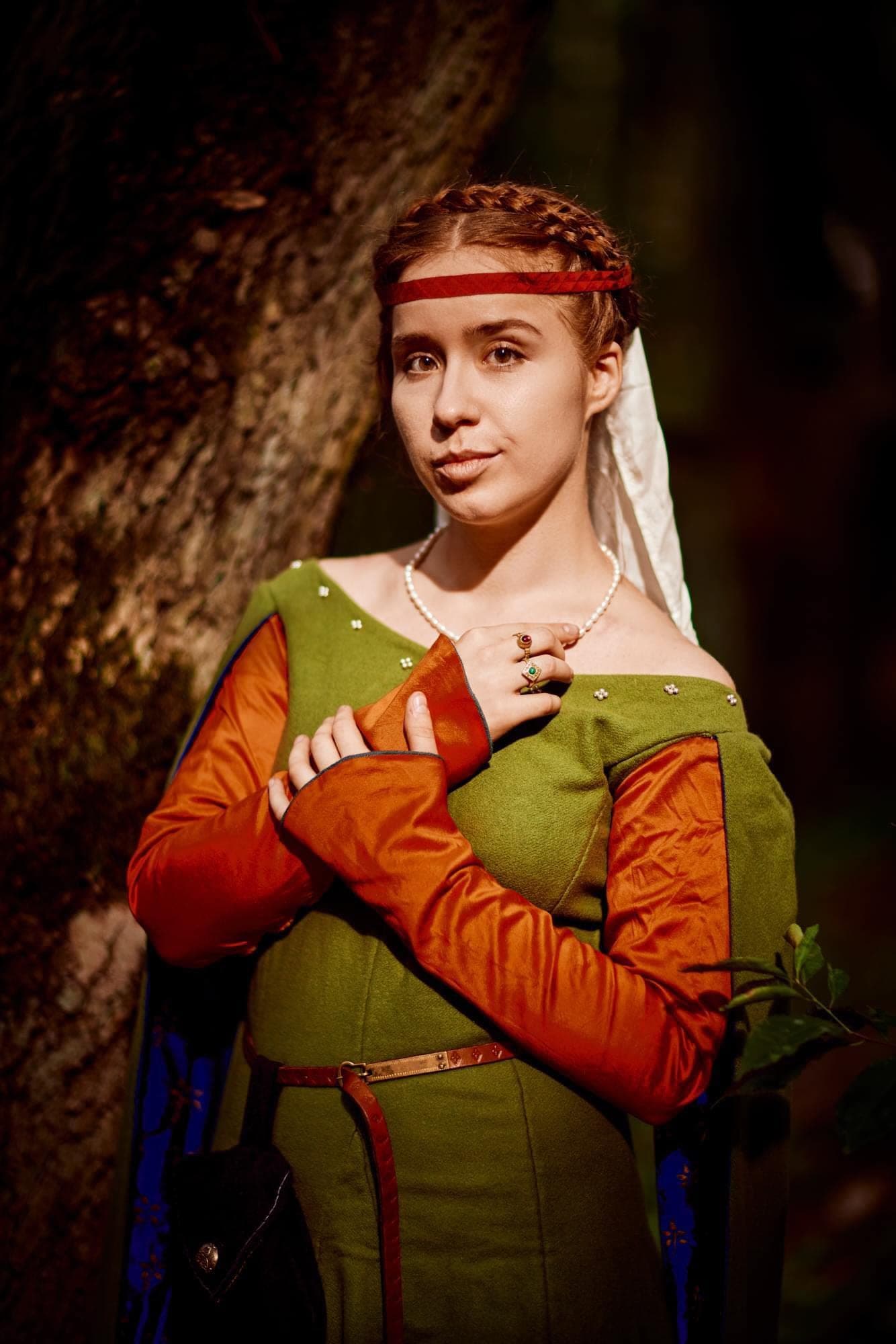Musician in a green medieval dress in the forest