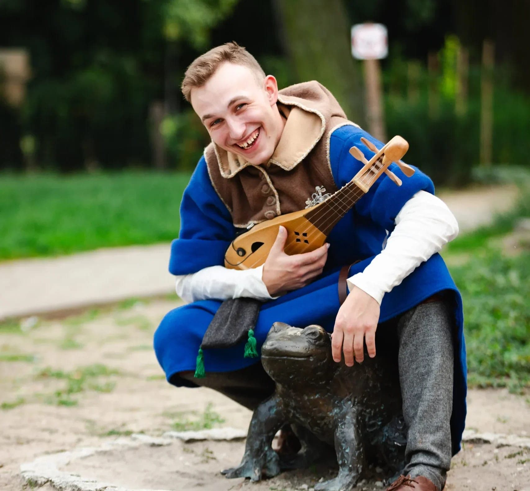 Musician with a gittern by a frog statue